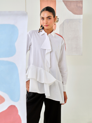 White asymmetric shirt paired with black pants with floral patch detail