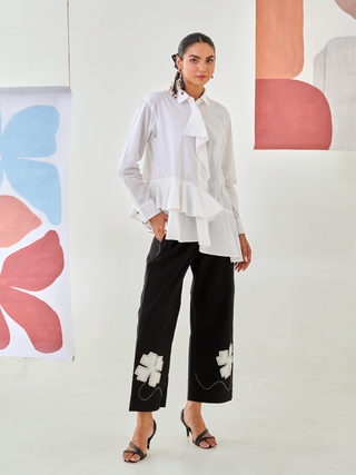 White asymmetric shirt paired with black pants with floral patch detail