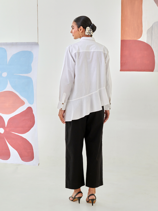White asymmetric shirt paired with black pants with floral patch detail
